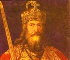 Portrait of a regal king in a jeweled crown and ornate robes, holding a staff or scepter.