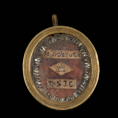 Reliquiario tondo dorato contenente il Santo Prepuzio con iscrizione latina 'De Praepotia D.N.J.C.' su sfondo di velluto rosso