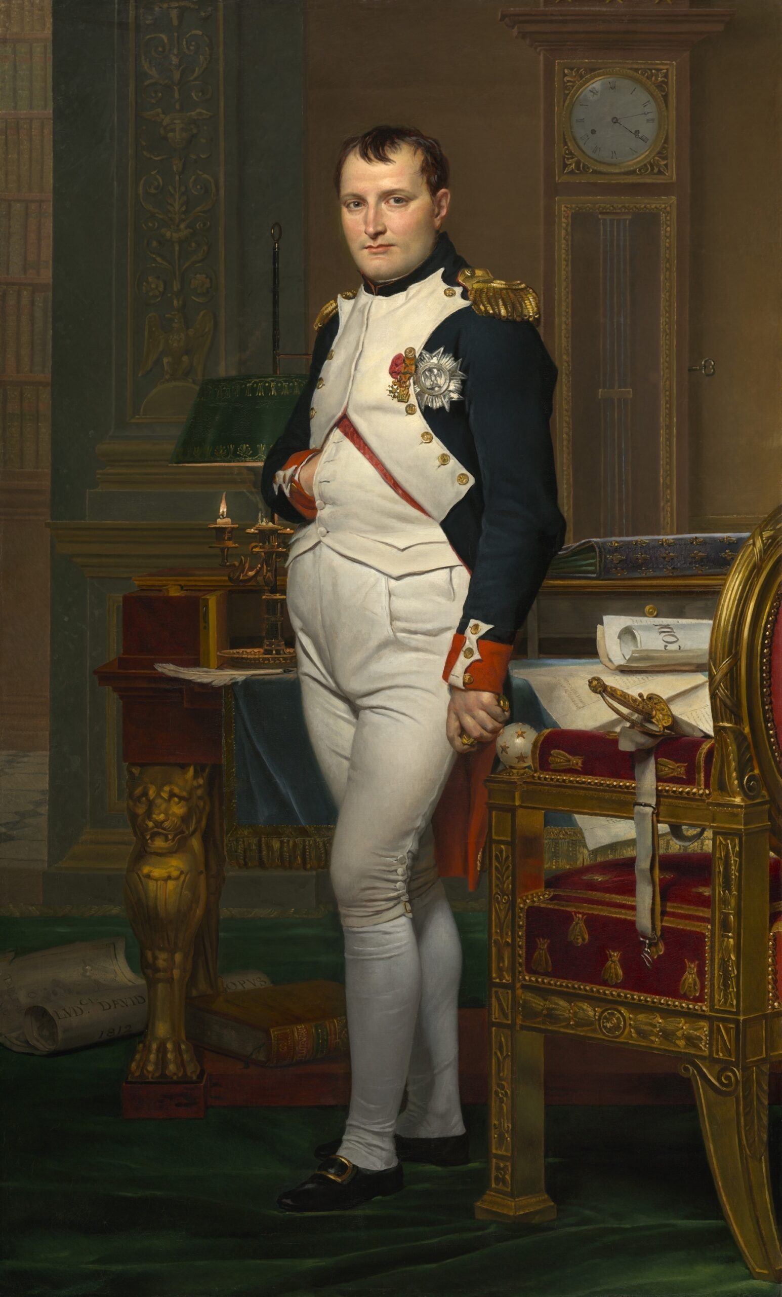Portrait of a 19th-century military officer in white trousers and dark blue coat with gold epaulettes and medals, standing beside an ornate desk and tall clock in a richly decorated room.