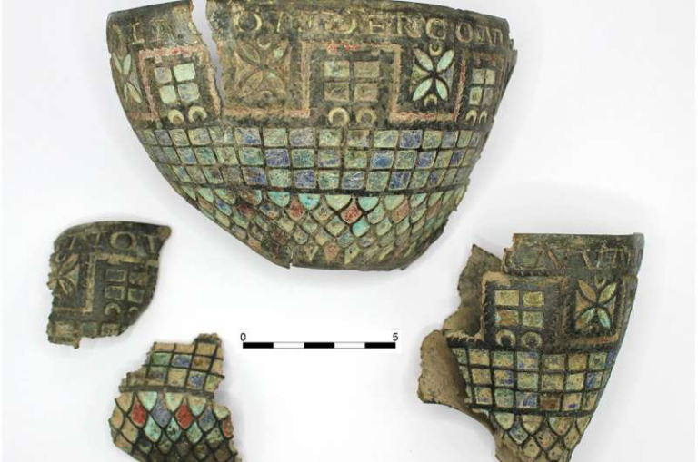 Fragmented ceramic vessel with turquoise, blue-green, and red mosaic tiles and geometric borders on a white background with a 5 cm scale bar.