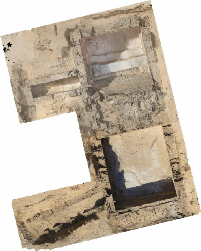 Aerial view of a desert archaeological dig with rectangular stone foundations and exposed trenches.