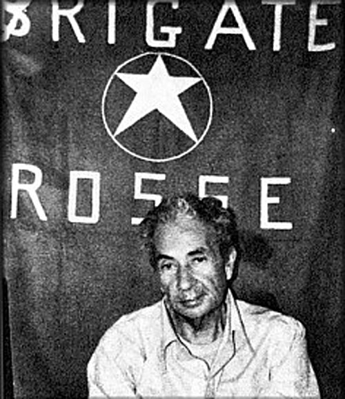 Il caso Moro come lente di ingrandimento - Scripta Manent Italia Fotografia in bianco e nero di Aldo Moro prigioniero delle Brigate Rosse, seduto davanti a uno striscione con la scritta Brigate Rosse e la stella a cinque punte, durante il sequestro del 1978