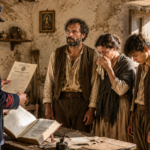 Officer in a vintage uniform reads a document to a distressed family inside a rustic stone-walled room, as a horse stands outside.