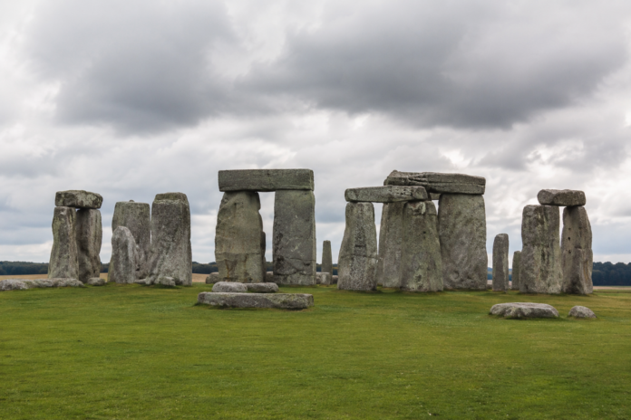 Stonehenge Stonehenge-style monument: a circle of large upright stones with horizontal lintels on a grassy field under a cloudy sky