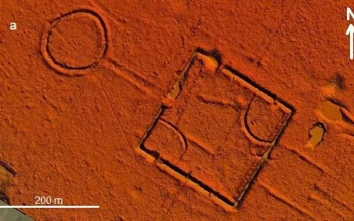Underwater view of a sunken square frame on a reddish seabed, with circular rings nearby and a 200 m scale bar for size reference.