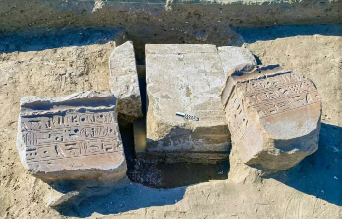 Three carved stone blocks with hieroglyphic inscriptions laid in an excavation trench.