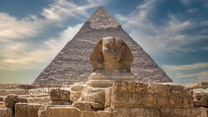 Sfinge e Piramide The Great Pyramid of Giza rises behind the Sphinx statue with ancient stone blocks in the foreground.