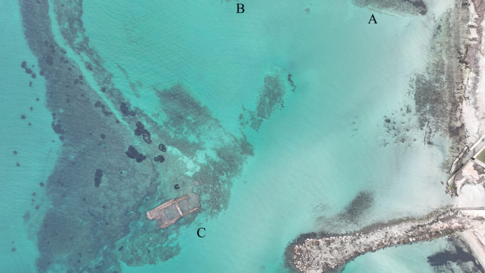 Vernole Aerial view of turquoise sea with a partially submerged wreck near a rocky jetty, labeled A, B, and C to mark points of interest.